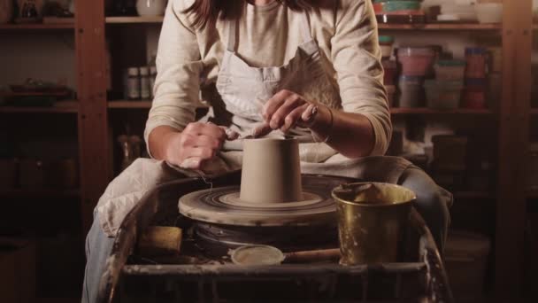 Laboratorio di ceramica mani femminili tagliare la parte superiore della pentola di argilla con una stringa - Filmati, video
