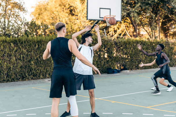 Man passing a ball during a basketball game between friends in an outdoor court - 写真・画像