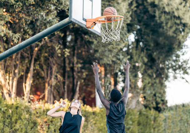 Ball geht in einen Basketballkorb, während einige multiethnische Freunde spielen - Foto, Bild