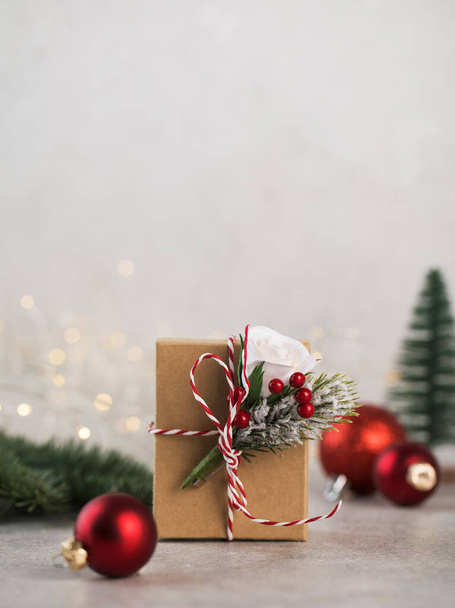  Christmas gift box on a background of Christmas tree branches, red Christmas balls and Christmas lights. Copy space. - Foto, afbeelding