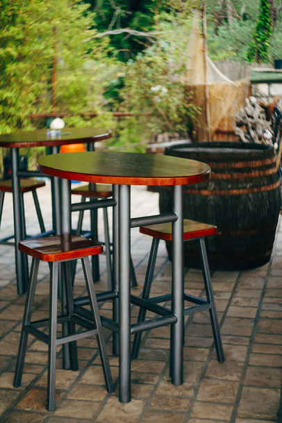 Wysoki metalowy stół z drewnianym blatem i niskimi stołkami w ulicznej kawiarni - Zdjęcie, obraz