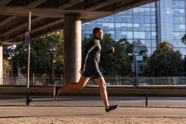 young man running outdoors under bridge - Valokuva, kuva