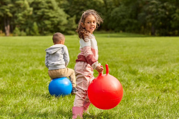 happy children bouncing on hopper balls at park - Фото, изображение