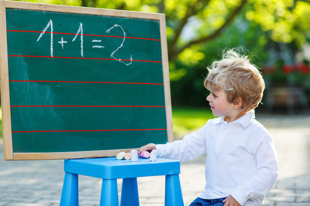Little boy at blackboard practicing mathematics - Foto, Imagem