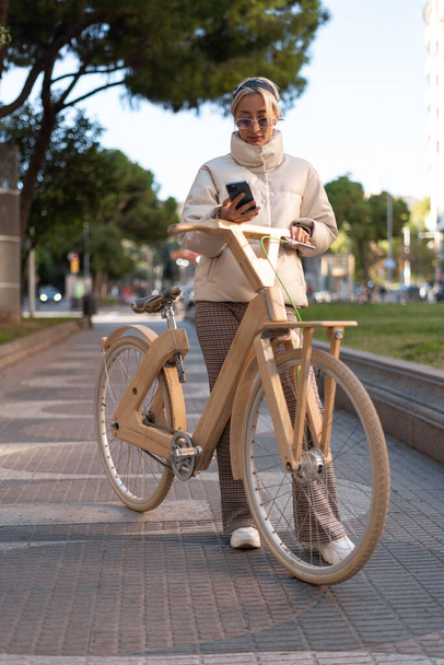 公園内の携帯電話を使用してトレンド自転車 - 写真・画像
