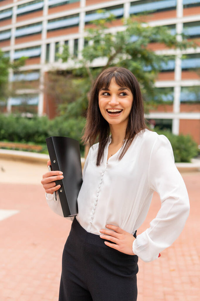Smiling caucasian businesswoman with clipboard on city street feeling happy after successful deal - Foto, Bild