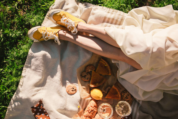 kobieta nogi na koc mając piknik na zachód słońca jedzenie napój na świeżym powietrzu lato - Zdjęcie, obraz
