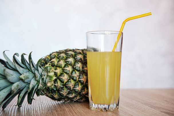 Freshly made pineapple juice on a wooden table. Place for text. Pineapple juice in a glass on a light background. - Zdjęcie, obraz