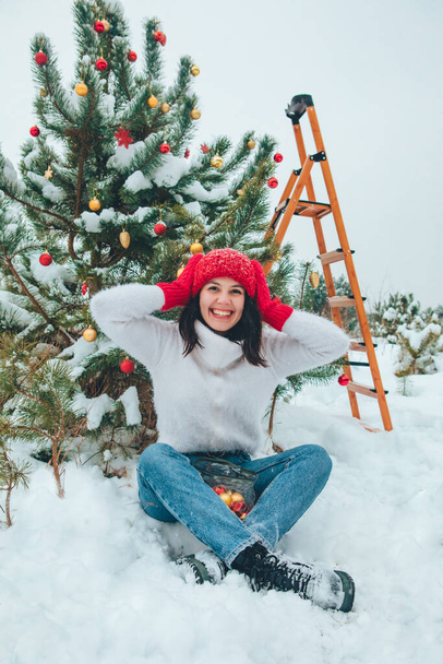 hermosa mujer decorando árbol de Navidad al aire libre - Foto, imagen