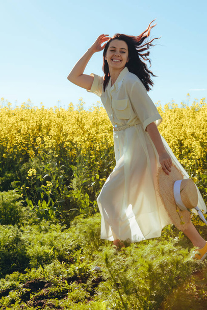 beautiful woman standing in rapeseed field summertime - Photo, Image