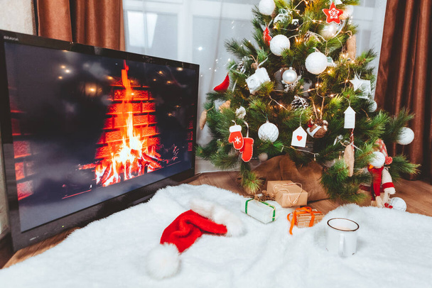 Lviv, Ουκρανία - 15 Δεκεμβρίου 2021: Θέα στο τζάκι στην οθόνη. τηλεόραση κοντά στο χριστουγεννιάτικο δέντρο αντίγραφο χώρο - Φωτογραφία, εικόνα