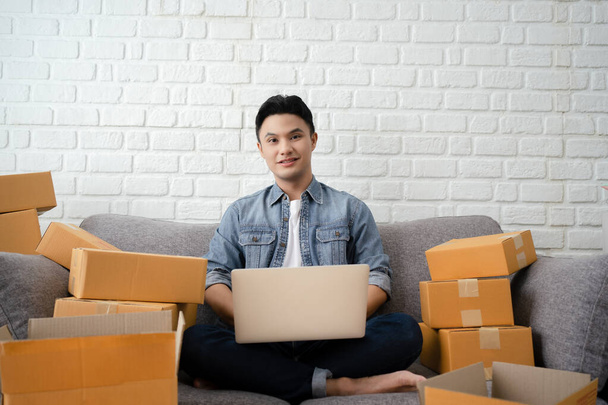 Asian businessman owner working at home with packing box on workplace - online shopping SME entrepreneur or online selling concept - Фото, изображение