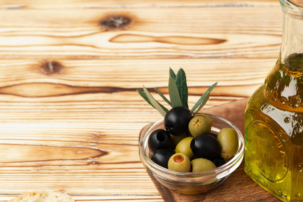 Olives and bottle of olive oil on wooden background - Photo, image