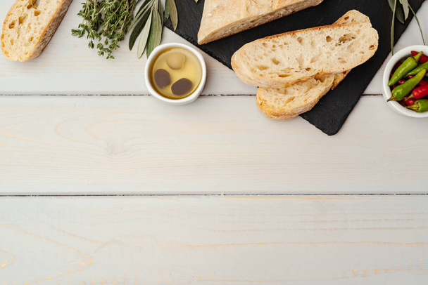 Italian ciabatta bread with olive oil on wooden background - Zdjęcie, obraz