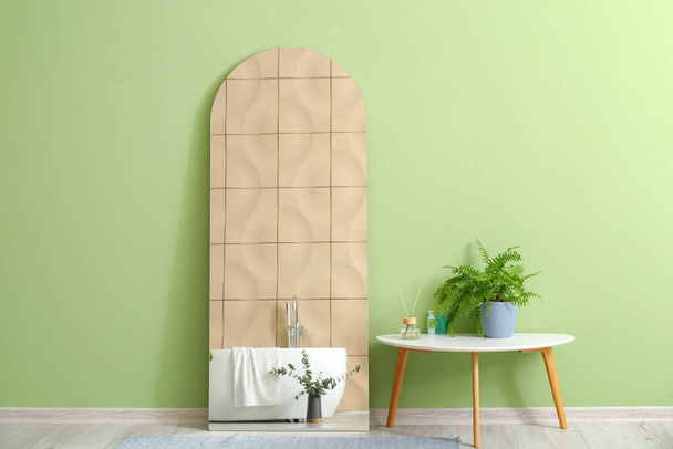 Espejo y mesa con planta de interior cerca de la pared verde - Foto, Imagen