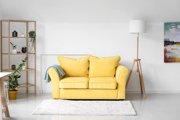 Innenraum eines hellen Wohnzimmers mit gelbem Sofa, Regal und Pflanzen - Foto, Bild