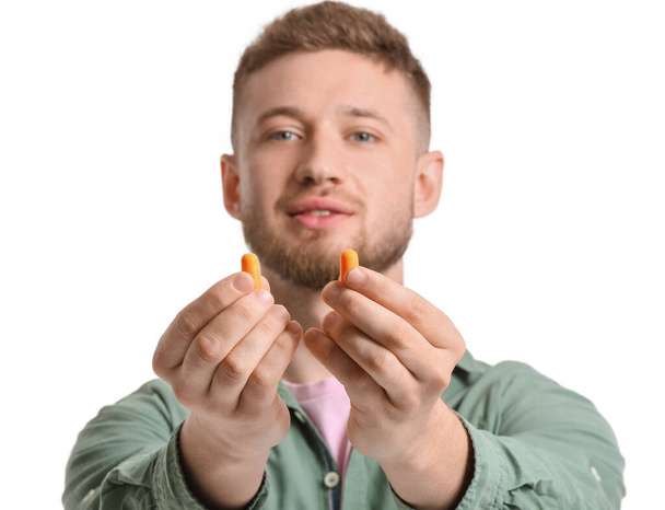 Young man with ear plugs on white background - Photo, Image
