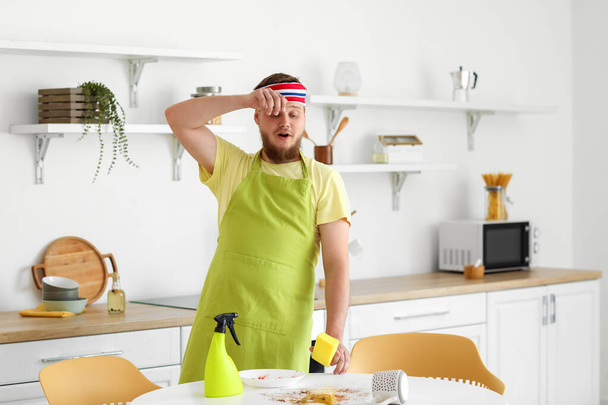 Young man tired of cleaning dining table in kitchen - Photo, Image