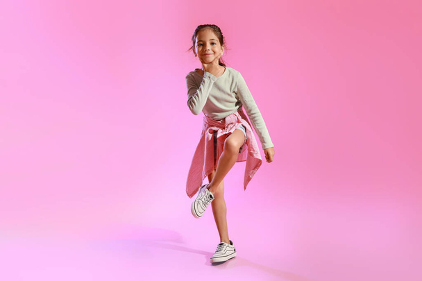 Imádnivaló kislány táncol rózsaszín háttér - Fotó, kép