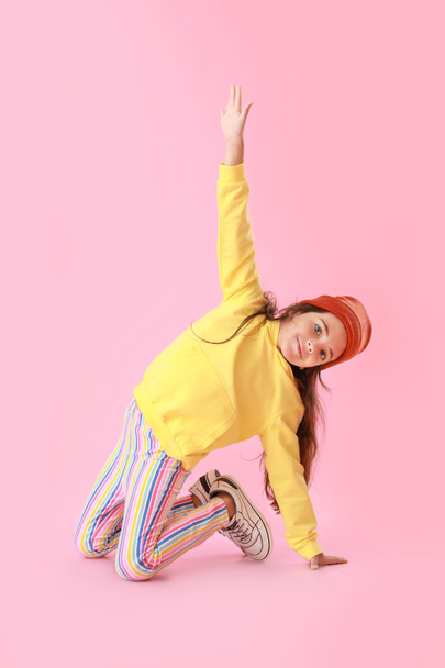 Urocza dziewczynka w żółtej bluzie tańcząca na różowym tle - Zdjęcie, obraz