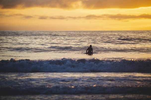 A landscape view of sea waves and a person swimming at sunset. Newport Beach, California - Φωτογραφία, εικόνα