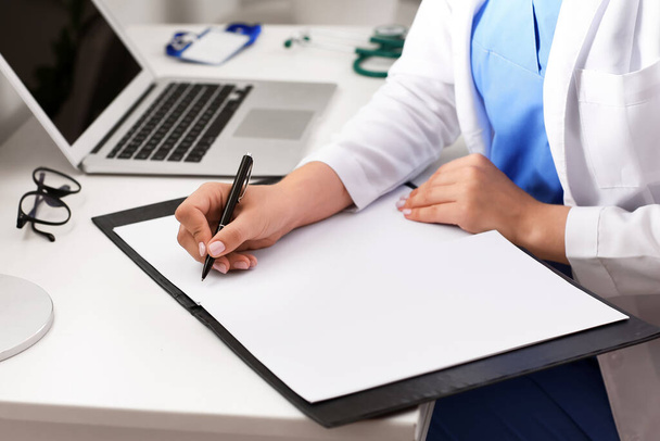 Ärztin schreibt in Mappe am Tisch, Nahaufnahme - Foto, Bild