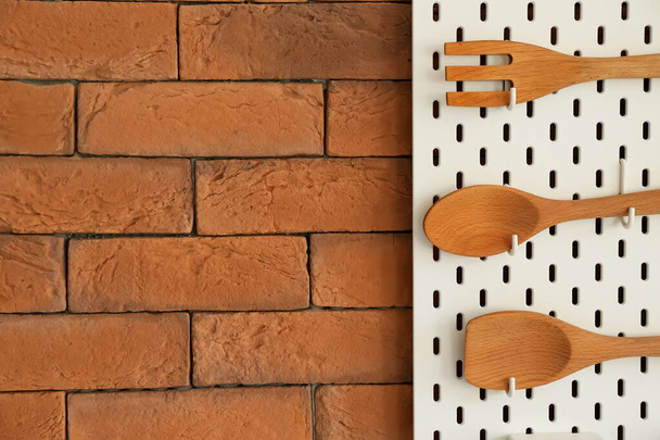 Peg deska s dřevěnými stěnami zavěšenými na cihlové stěně, detailní záběr - Fotografie, Obrázek