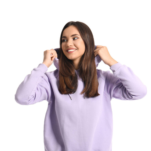 Mooie jonge vrouw in stijlvolle hoodie op witte achtergrond - Foto, afbeelding