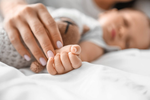 Hands of sleeping baby and mother on bed, closeup - Foto, immagini