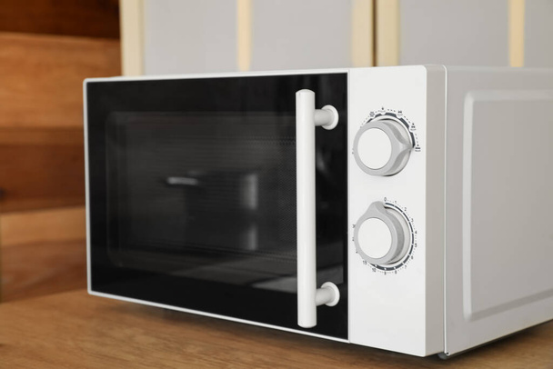Microwave oven on wooden tabletop in kitchen - Fotó, kép