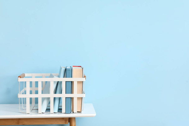 Кошик з книгами на столі біля синьої стіни
 - Фото, зображення