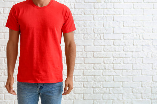 Handsome young man in stylish t-shirt on white brick background - Photo, Image