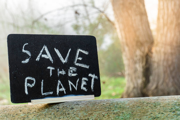 The cardboard sign with the slogan Save the Planet on the tree with the blurred background - Zdjęcie, obraz