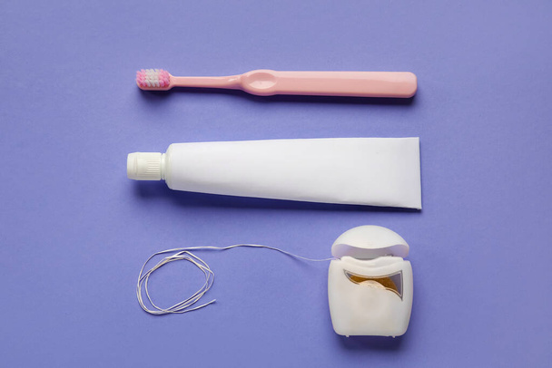 Dental floss with tooth brush and paste on purple background - Photo, Image