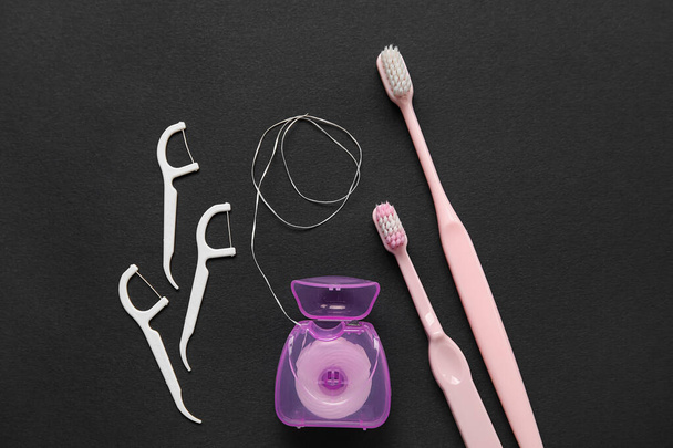 Dental floss met tandenstokers en borstels op zwarte achtergrond - Foto, afbeelding