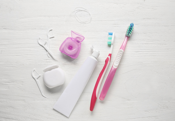 Zahnseide, Zahnstocher, Paste und Bürsten auf weißem Holzgrund - Foto, Bild