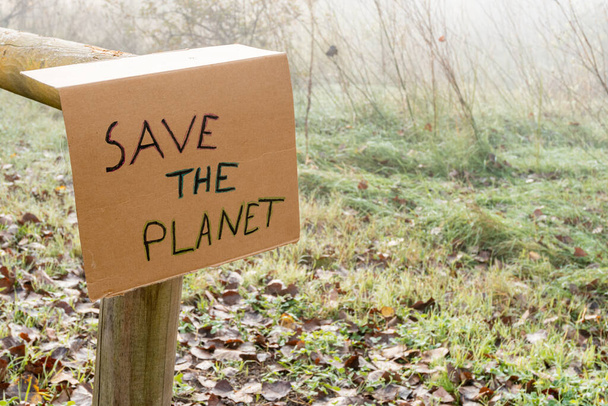 The cardboard sign with the slogan Save the Planet on the log with the blurred background - Φωτογραφία, εικόνα