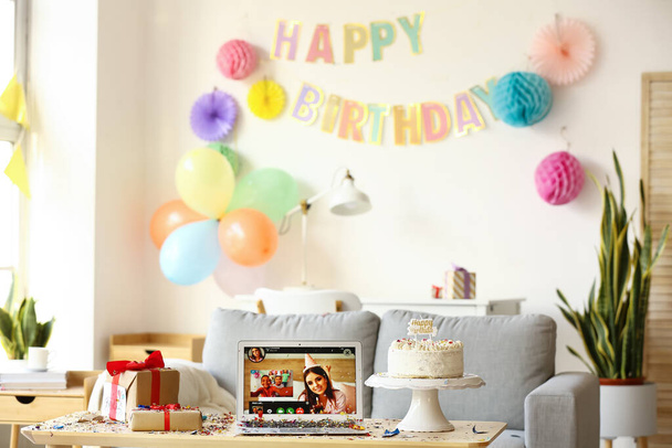 Kannettava tietokone, lahjat ja kakku pöydällä huoneessa. Syntymäpäivän viettäminen verkossa sepelvaltimotautiepidemian vuoksi - Valokuva, kuva