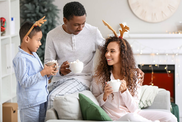 Famiglia afroamericana felice che beve gustosa cioccolata calda a casa la vigilia di Natale - Foto, immagini