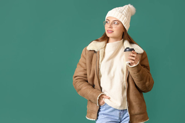 Gyönyörű fiatal nő téli ruhák és egy csésze kávé színes háttér - Fotó, kép