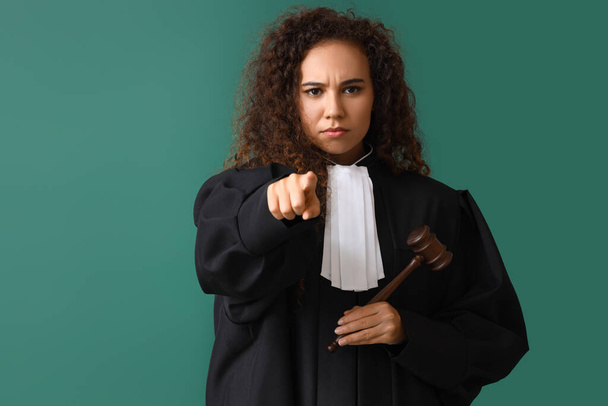 Strenge Richterin mit Hammer, der auf farbigen Hintergrund auf den Betrachter zeigt - Foto, Bild