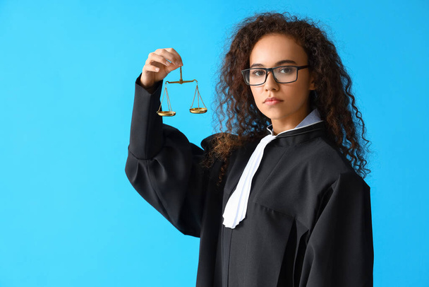 Portrait de juge féminine avec des échelles de justice sur fond de couleur - Photo, image