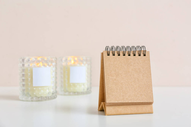 Leere Bastelkalender und brennende Kerzen auf dem Tisch vor hellem Hintergrund - Foto, Bild