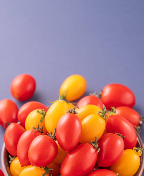 Fresh cherry tomatoes in a wooden bowl isolated on a blue background, close up, copy space - Valokuva, kuva