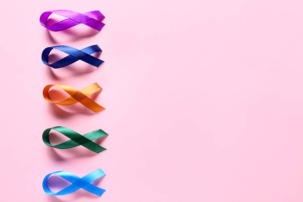 Different awareness ribbons on pink background. World Cancer Day - Photo, Image