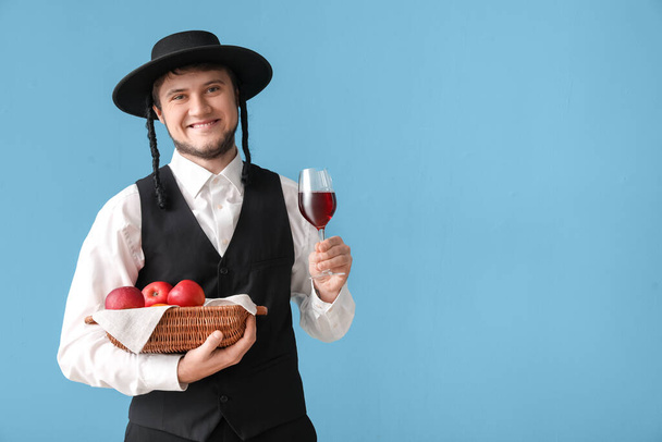 Joven judío con frutas en cesta y copa de vino sobre fondo gris - Foto, imagen