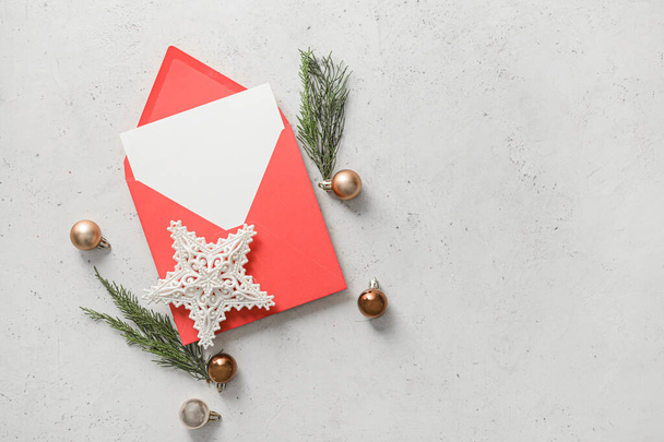 Φάκελος με άδεια ευχετήρια κάρτα και χριστουγεννιάτικα στολίδια σε ανοιχτό φόντο - Φωτογραφία, εικόνα