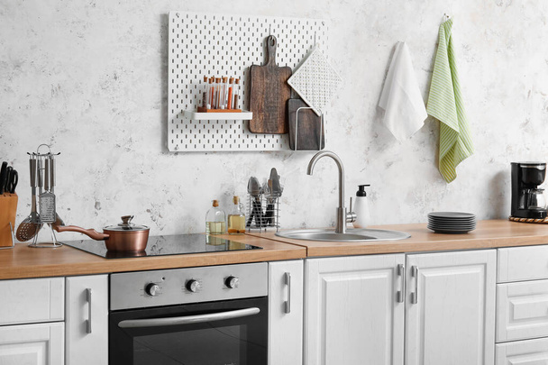 Interieur der modernen Küche mit weißen Arbeitsplatten, silberner Spüle und Geschirr - Foto, Bild