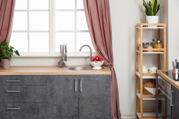Interieur der modernen Küche mit grauen Arbeitsplatten, silberner Spüle und Regal - Foto, Bild