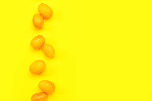 Tasty kumquat fruits on yellow background - 写真・画像